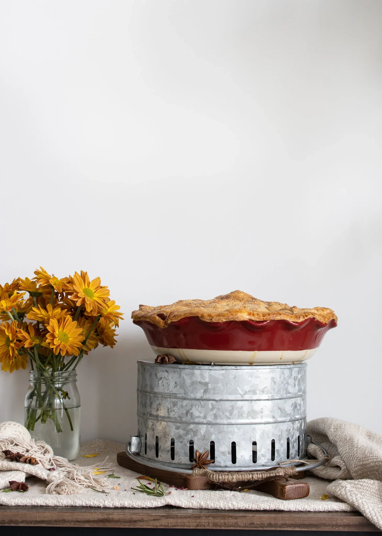 Side-angle portrait of a Classic Apple Pie baked in a deep red ceramic pie dish