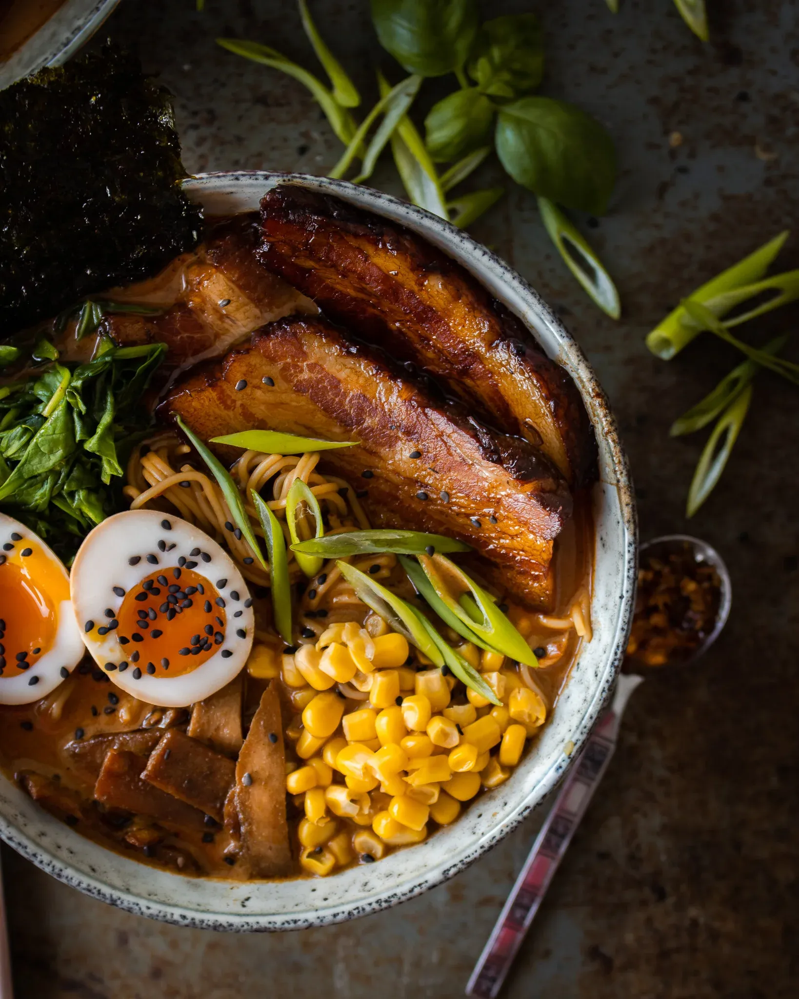 Overhead close-up of Use What You Have Ramen in a rustic speckled ceramic bowl filled with rich amber miso-tonkotsu broth