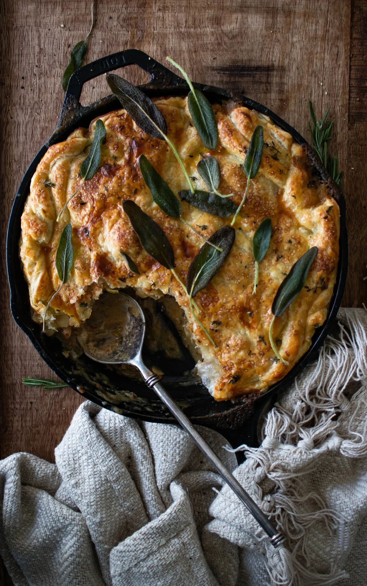 Overhead view of a chicken pot pie baked in a large black cast iron skillet on a dark wooden board