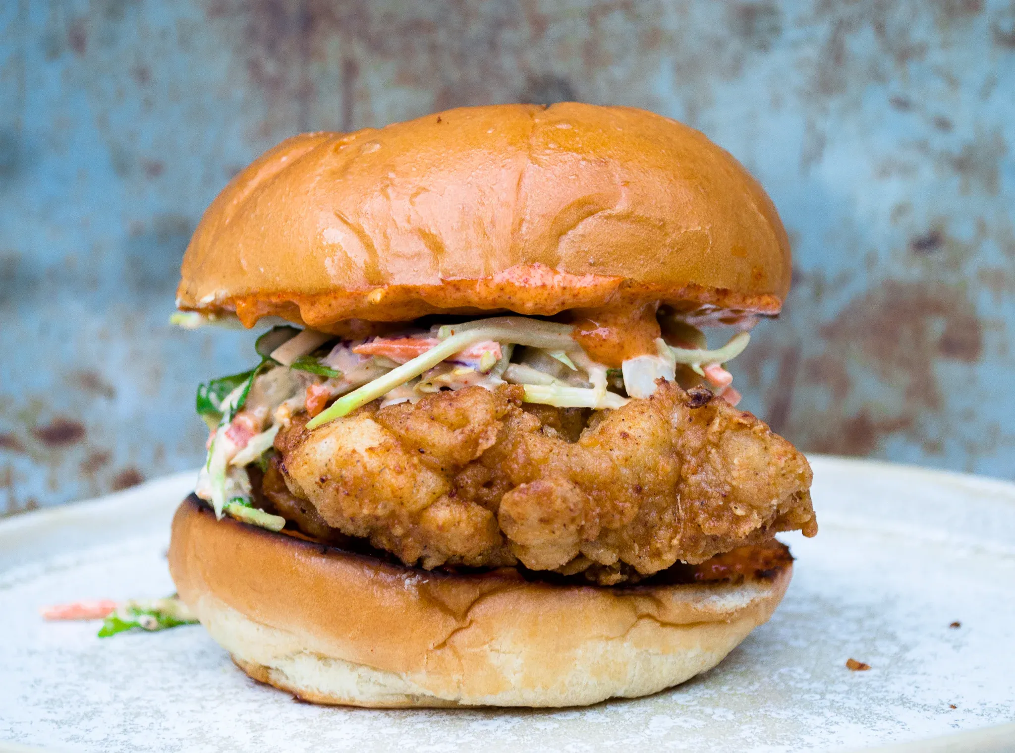 Fried Chicken Sandwich with Creamy Slaw and Sriracha Aioli served on a golden toasted brioche bun