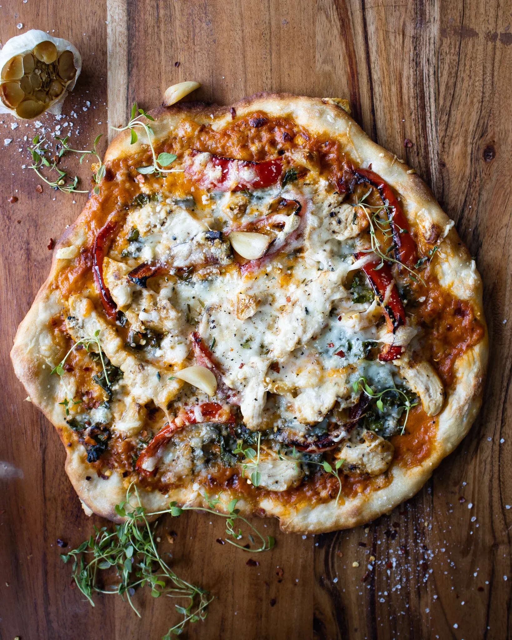 Overhead view of a whole chicken alla vodka pizza on a rustic wooden board