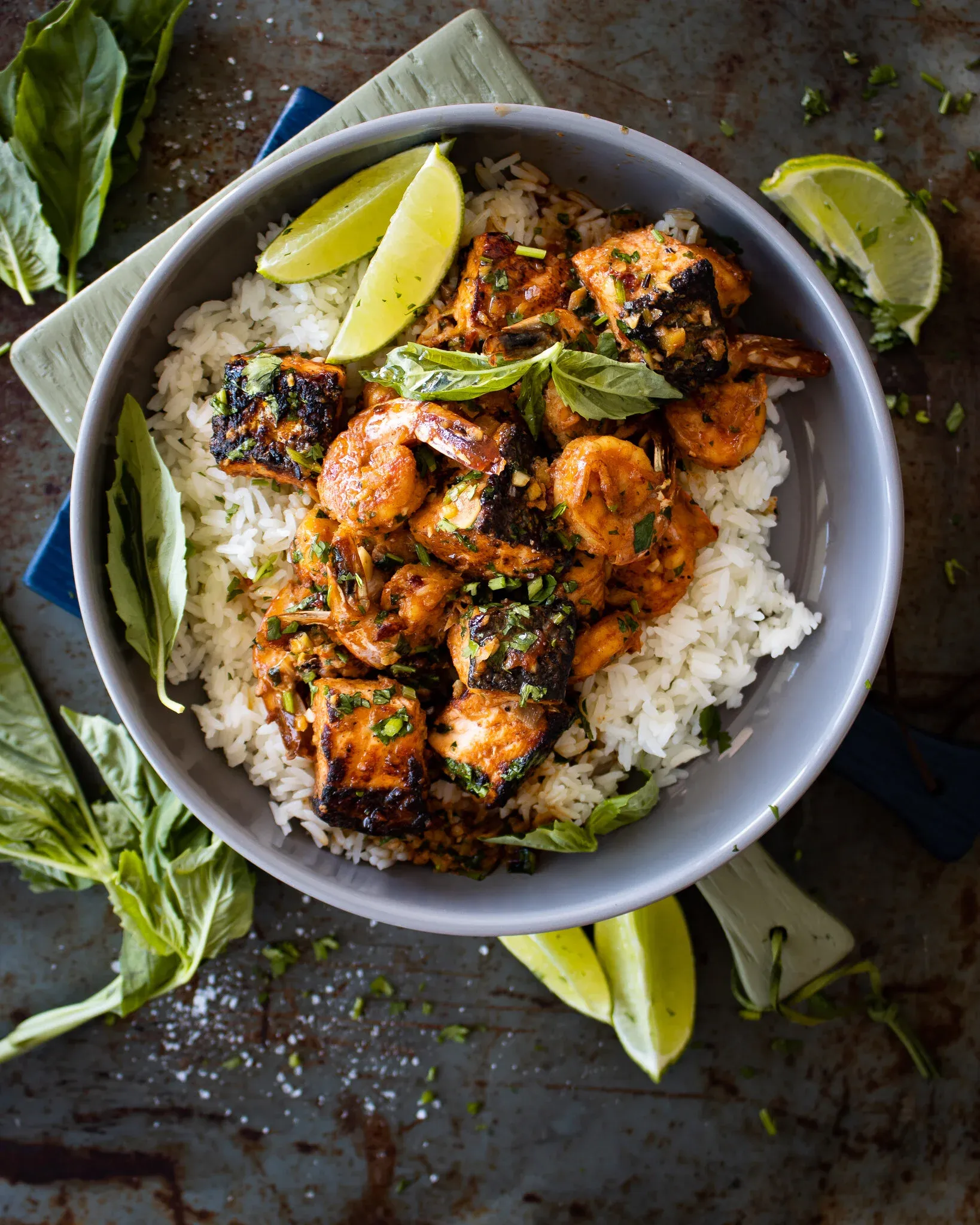 Overhead view of a gray bowl of Honey Garlic Salmon and Shrimp Bowl on a dark metal surface