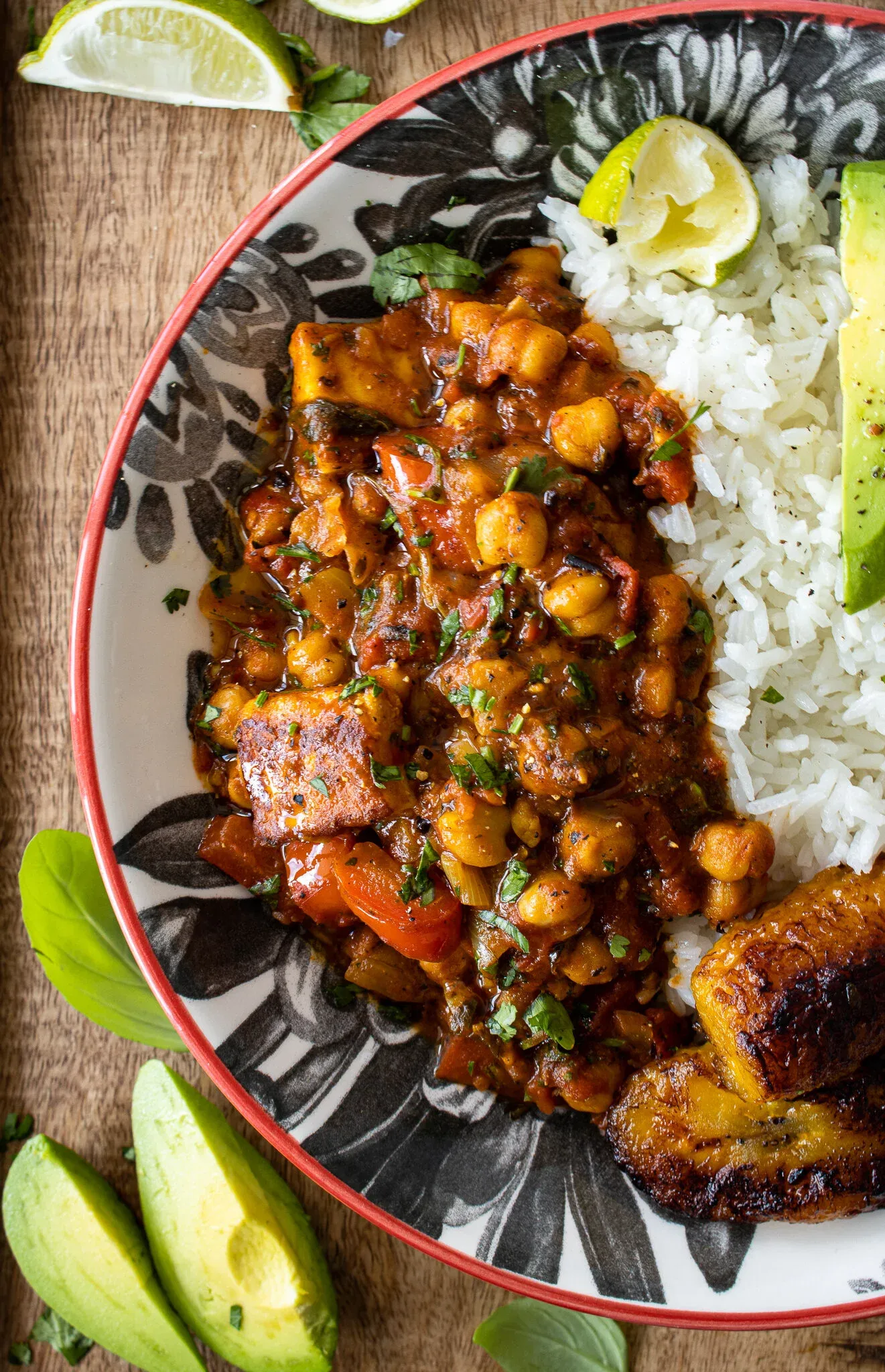 Overhead close-up of Vegetarian Chickpea and Paneer Picadillo in a decorative black-and-white floral ceramic bowl with a red rim