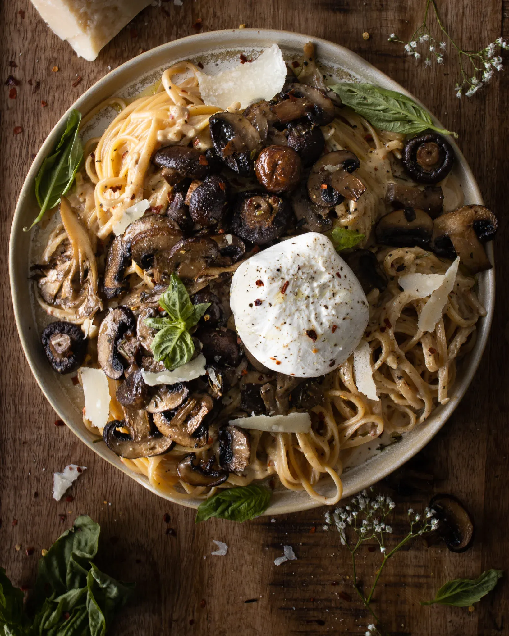 Overhead shot of a wide speckled ceramic bowl of mascarpone pasta with roasted mushrooms and burrata