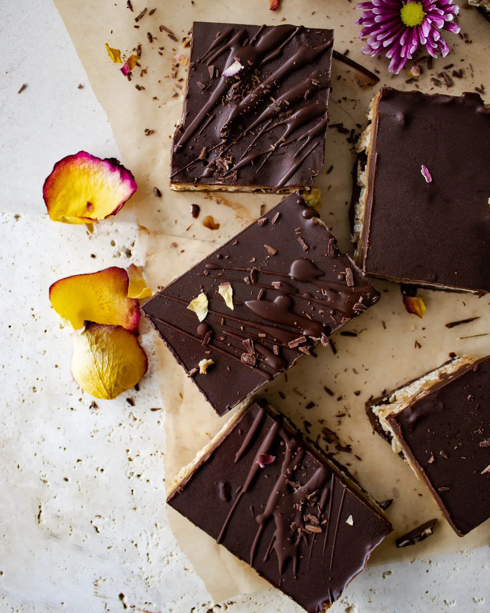 Overhead flat-lay of six No Bake Dark Chocolate Peanut Butter Oat Bars on parchment paper over a white marbled surface