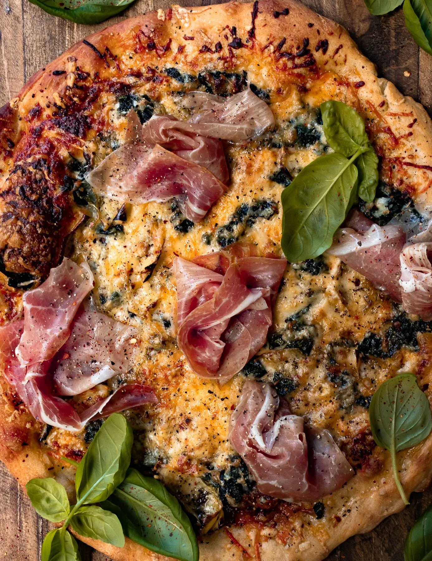 Spinach and Artichoke Pizza in a very close overhead crop on a wooden board