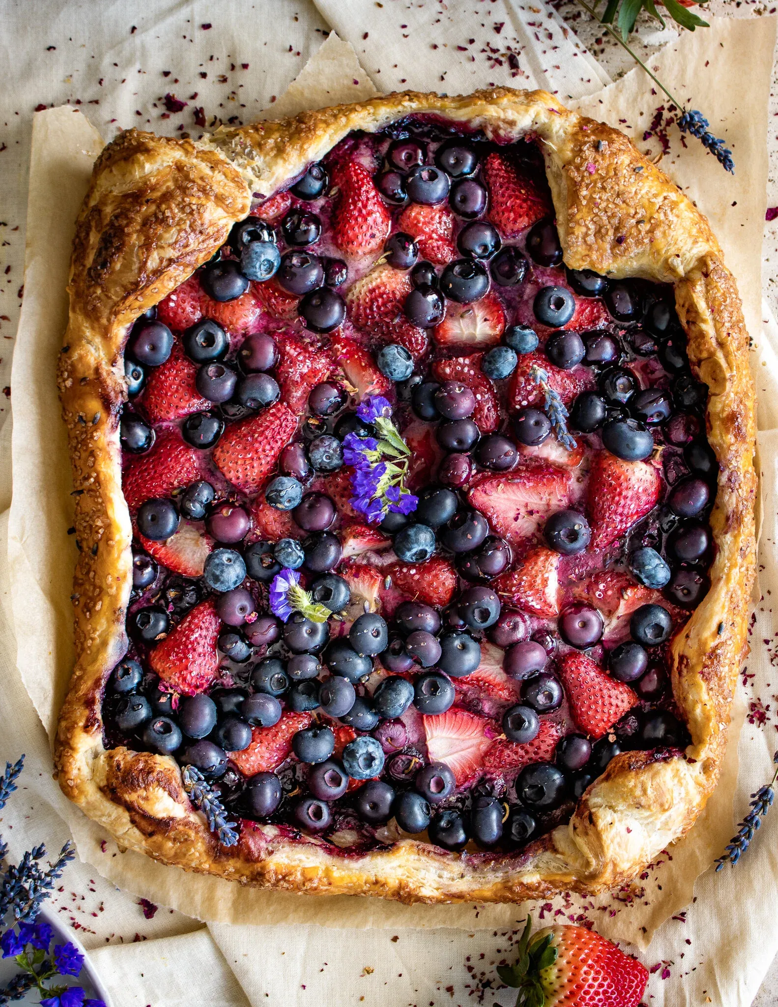 Overhead flat-lay of a square puff pastry berry galette on parchment paper